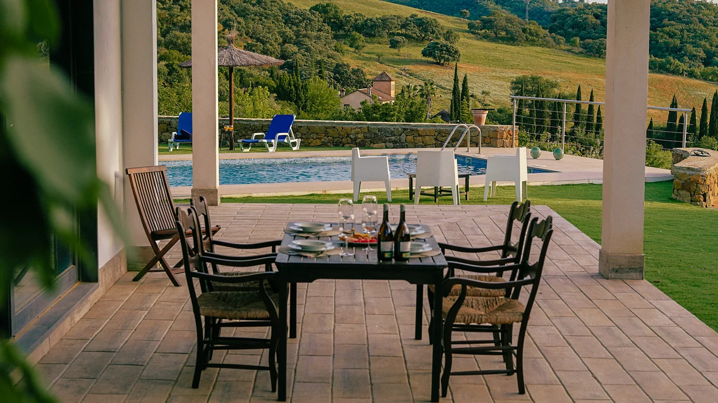 Porche de La Huerta con mesa frente al jardín y la piscina